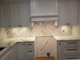 Hold each tile sheet straight across the top and set down your spacers before pressing tile firmly and evenly into the mortar. Crooked Marble Herringbone Backsplash Install Acceptable