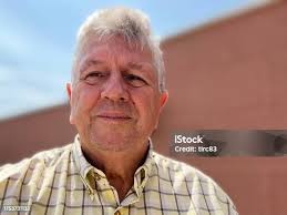 Elderly Man Sitting In Front His House At Dawn Stock Photo