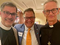 JPB Founder, Fr. Nicholas (center with orange tie) with Dean Richard Sewell  of St. George's College, Jerusalem (left) at a reception in the home of  Linnet Deily (center) in Houston. Also there