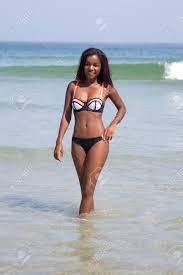 An Attractive Black Bikini Model Walking In The Water By The Seashore While  Looking At The Camera And Smiling Stock Photo, Picture and Royalty Free  Image. Image 59966264.