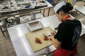 U.S. Marine Corps Cpl. Valerie Daniel chops bacon for