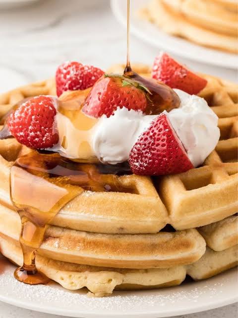 Belgian Waffles stacked with strawberries, whipped cream, and maple syrup