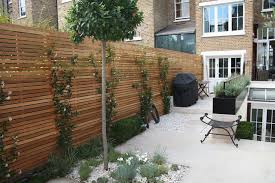 Kleiner Schwarzer Stuhl Und Ein Garten Mit Gr Nen B Umen Und Einem Zaun Aus Holz Und Mit Gr Nen Kletterpflan In 2020 Modern Backyard Privacy Fence Designs Fence Design
