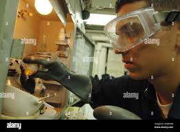 US Navy Engineman 3rd Class adds drops of chloride reagent into a boiler  water sample as he performs boiler water tests in the oil lab Stock Photo