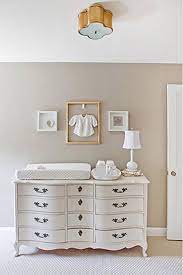 A serene painting of the sky graphically hangs from nautical rope above toy storage, while tin whales spouting stars glide across the crib wall. The 12 Best Warm Neutrals For Your Walls Nursery Paint Colors Nursery Design Neutral Nursery Changing Table