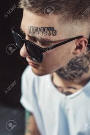 Jeune Homme Avec Des Tatouages Sur Le Visage Et Le Cou Posant Dans Des Lunettes De Soleil Noires A La Recherche De Suite Banque D Images Et Photos Libres De Droits Image 86190393
