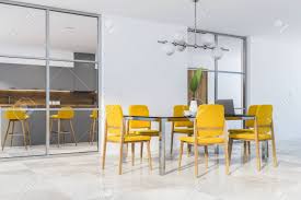A luxe combination of yellow and black lays the foundation for sophisticated social gatherings. Corner Of Modern Dining Room With White Walls Tiled Floor Black Table With Laptop And Yellow Chairs Kitchen With Bar In The Background 3d Rendering Stock Photo Picture And Royalty Free Image