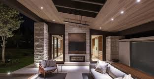 The polished black metal exteriors of the fireplace contrasts the stone walls in terms of texture and feel. Pool Guest House Outdoor Fireplace Stone Patio Modern Rustic Luxury Design Buechel Stone