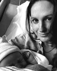 She's propped up in the hospital bed, sore and desperately tired, with a  newborn curled