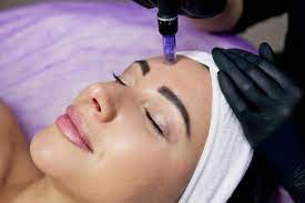 beautician makes injections into the forehead of mesotherapy with a microneedle