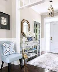 Flanking a white scalloped mirror, light blue double gourd lamps sit on a white credenza placed on charming tan and blue foyer is covered in white and blue wallpaper and accented with a round blue. Beautiful Entryway With Light Blue Chair And Console Table Entryway Consoletable Entrwaydecor Decortingideas Springd Light Blue Chair Home Decor Interior