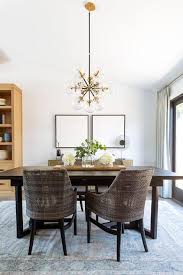 Brown Wicker Chairs At A Dark Brown Wooden Dining Table Illuminated By An Atom Chandelier In A Trans Dark Dining Room Dining Room Table Decor Brown Dining Room