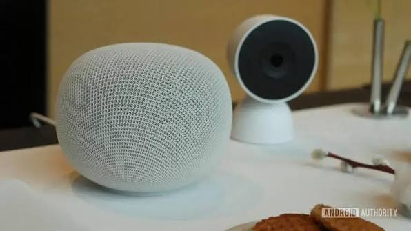 Imagem de um Google Home Speaker com um anel de luz na base, em uma superfície clara.