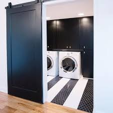 Small laundry room with nook sink and cabinet on dark gray tile floor set against white cabinets and beige walls. Black And White Laundry Rooms Design Ideas