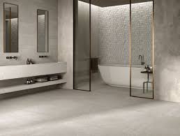 A gray porcelain tiled floor leads to a chrome and glass contemporary bathroom features a seamless glass walk in shower lined with blue glass subway shower tiles and a shower bench above the gray. Bathroom Tiles Kronos Ceramiche Floor Coverings In Porcelain Stoneware