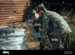 220718-N-PI330-1016 NAVAL STATION ROTA, Spain (July 18, 2022) Lt. j.g. Caleb  Tilley, left, and Steelworker Constructionman Jason Dulerain, assigned to  Naval Mobile Construction Battalion 133 (NMCB 133), set up c-wire during a