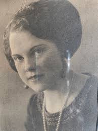 Damaged portrait of Mattie Edwards wearing plaid collared jacket with plaid  cuffs and embroidered scoop neck blouse seated at table. (1920) I repaired  what I could, but the glass plate was cracked