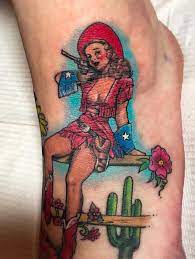 This pin up tattoo design is one of many that depict seductively posed women performing what was believed to be a lady luck tattoo designs: Cowgirl Pinup This Was Much Blue Rider Tattoo Company Facebook