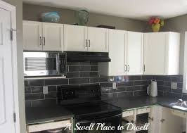 Black Subway Backsplashes Tile Above L Shaped White Cabinetry With Drawers And Locker Storage Black Grani Kitchen Tiles Kitchen Design Kitchen Tiles Backsplash