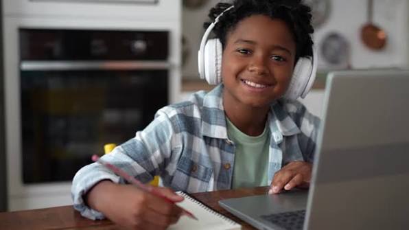 Child in headphones concentrating during a live online class at home, an example of good screen time for kids
