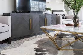 Black And Gold Accent Chair Light Gray Accent Chairs Lined With Black Piping Flank A Black Herringbone Tv Cabine Black And Gold Living Room Tv Stand Decor Living Room Living Room Tv Stand