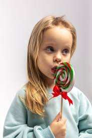 Portrait of funny little blonde girl with sweets lollipop in her hand
