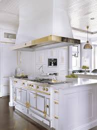 In the kitchen, a black and gold la cornue range and hood sit amongst green and yellow cabinets and antique french tiles. La Cornue Range And Hood Beck Allen Cabinetry