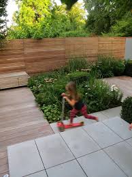 Contemporary Grey Sawn Sandstone Paving Is Complemented Beautifully By The Lush Planting In This Urban Garden Urban Garden Design Urban Garden Family Garden