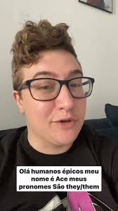 Vídeo ID: Ace sits in their living room wearing a black tshirt with the  asexual flag colors just visible