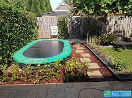 achtertuin trampoline ingraven boomschors groen beplanting achtertuin hovenieren zandbak