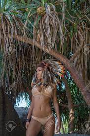 日当たりの良い夏の日に熱帯の木々 の間に立って脇ながら官能的なネイティブ ・ アメリカン ・ インディアンを探して女性着て裸ビキニとインドの羽帽子探しの写真素材・画像素材  Image 72172979