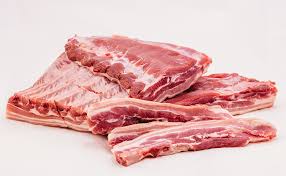 Flat lay com bife de costela cru no papel manteiga com faca de açougue, especiarias, batatas e alho. Suino Carnes Meireles