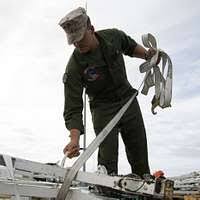 Sgt. Kyle Selman, bottom, and Cpl. Benjamin Cervantes rivet brackets into  the engine space of an F/A-18C Hornet.