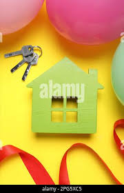Wooden house model, keys, red ribbon and balloons