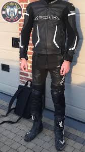 A photograph showing a slim biker wearing a two-piece leather racing suit  rated as Class AAA under EN 17092 and combined with premium sport motorcycle  boots certified as CE Level 2 -