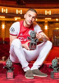 Girlfriend wears a red, sleeveless short dress and has auburn long hair. Hakim Ziyech Height Weight Age Family Facts Biography