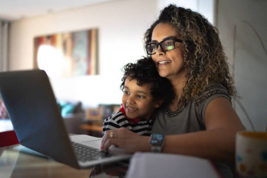 Parent sitting beside a child during an online lesson, choosing good screen time activities together