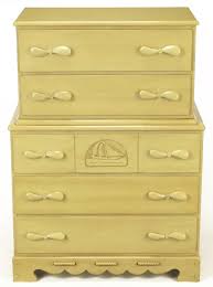 Standing on top of splayed legs that are characteristic of the retro look, this design showcases contrasting walnut panels and a white finish that are made to draw the eye. Pair Of Five Drawer Tall Chests With Propeller Pulls And Sailboat Reliefs At 1stdibs