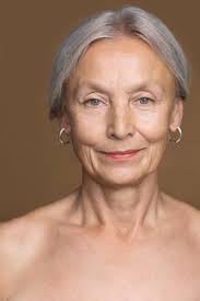 Porträt einer nackten älteren Frau mit grauen Haaren vor braunem  Hintergrund, lizenzfreies Stockfoto