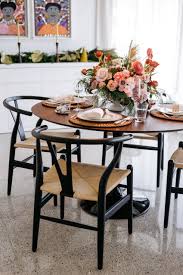Saarinen Dining Table With Wishbone Chairs And Tropical Christmas Tablescape Centerpiece And Garland Dining Table Centerpiece Log Centerpieces Dining Table