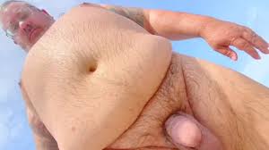 O velho homem de cabelos grisalhos gordo tem dia nu e cums na praia