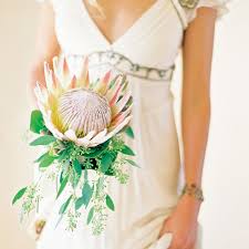Bridesmaids can also add their ceremony bouquets to vases on each table for a reusable centerpiece. King Protea Bridal Bouquets That Are Crazy Striking