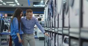 It's like they just came out of the washing machine!! Young Married Couple Man And Woman In Casual Clothes Appliances Store Choose To Buy Washing Machine For Home Open The Door Looking Into The Drum Compare The Design And Characteristics Of The