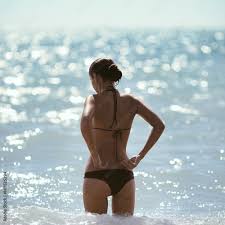 Fashion shot of young beautiful fit brunette girl in black bikini standing  on beach. Stock Photo | Adobe Stock