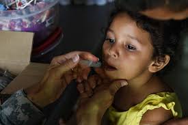 A young girl receives a dose of deworming medicine