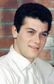 Tony Curtis Doing the publicity thing here, wearing a white short-sleeved  polo shirt, posing against a bare brick wall. 1955.