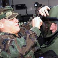 Dressed in Mission-Oriented Protective Postures level-4 (MOPP-4) gear, US  Air Force (USAF) SENIOR AIRMAN Anton Starkovich (left) and STAFF Sergeant  (SSGT) William Baird bag a simulated unexploded ordnance in order to dispose