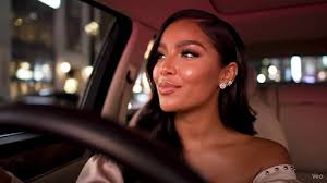 The prompt: Woman skin is light caramel, fluffy lashes, full gloss lips,  light glam, [Visual Aesthetic] , Evening hours. The inside of her Rolls  Royce glows with soft pink ambient lights, a mix of ...