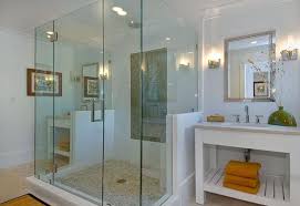 This bathroom with glass frameless shower with travertine tile and rain showerhead blends a few traditional elements such as the window and door trims, with a more modern element such as the rain shower, bathtub taps, and telephone shower in a chrome finish. 25 Glass Shower Doors For A Truly Modern Bath