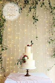 Blush Smooth And Textured Buttercream Wedding Cake With Gold Leaf And Fresh Flowers Ivy And Fairy L Cake Backdrops Fairy Light Backdrops Green Wedding Flowers
